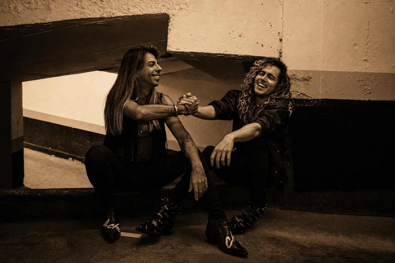 A dupla Be Boots em retrato urbano em tom sépia, rindo